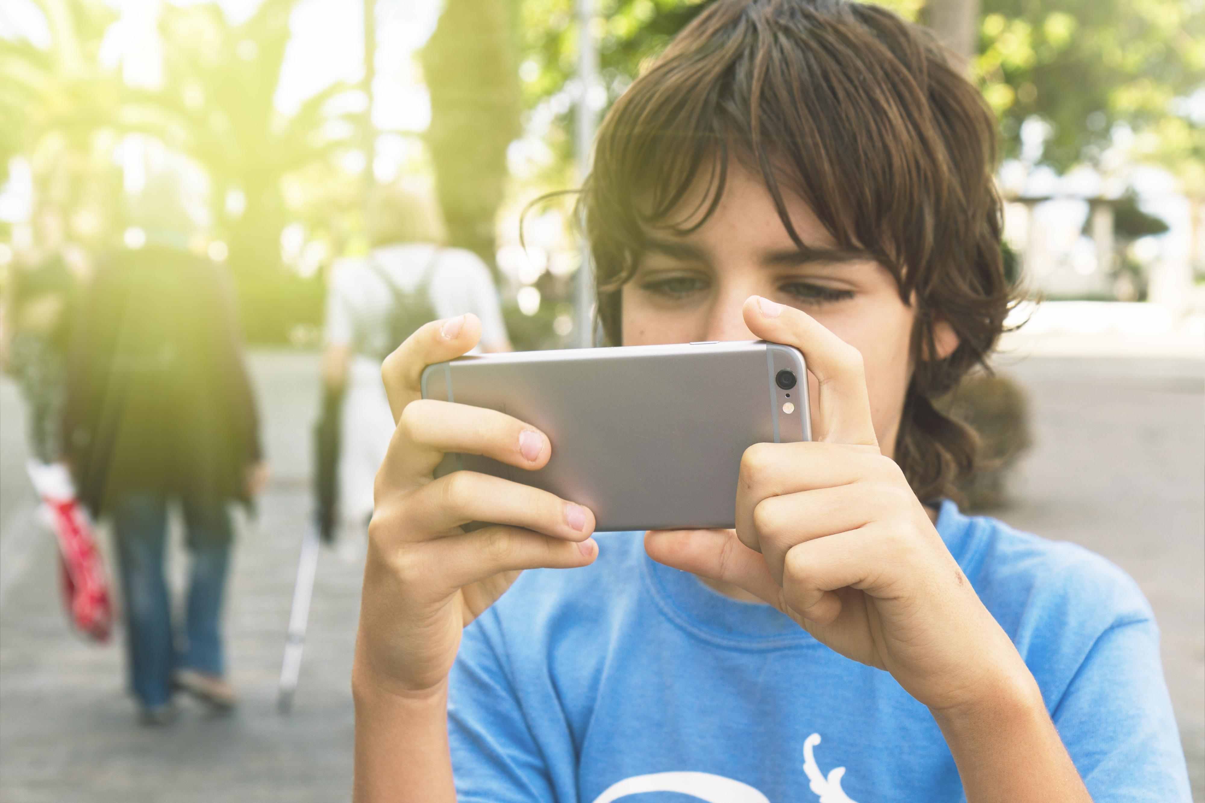 boy playing with smartphone in street