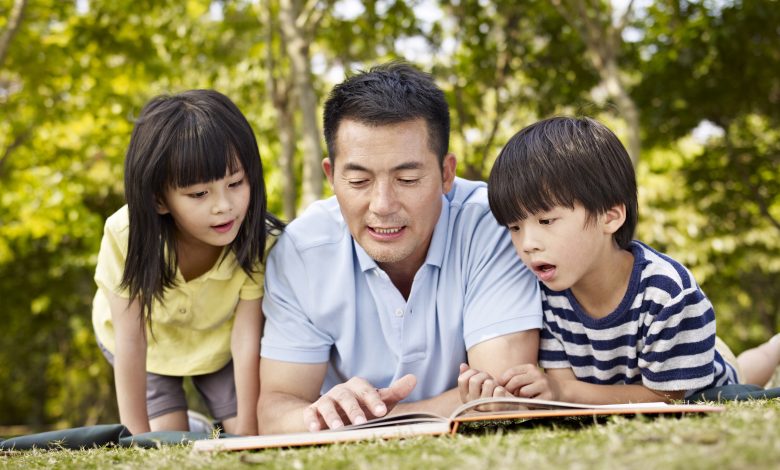 Father and children reading book together