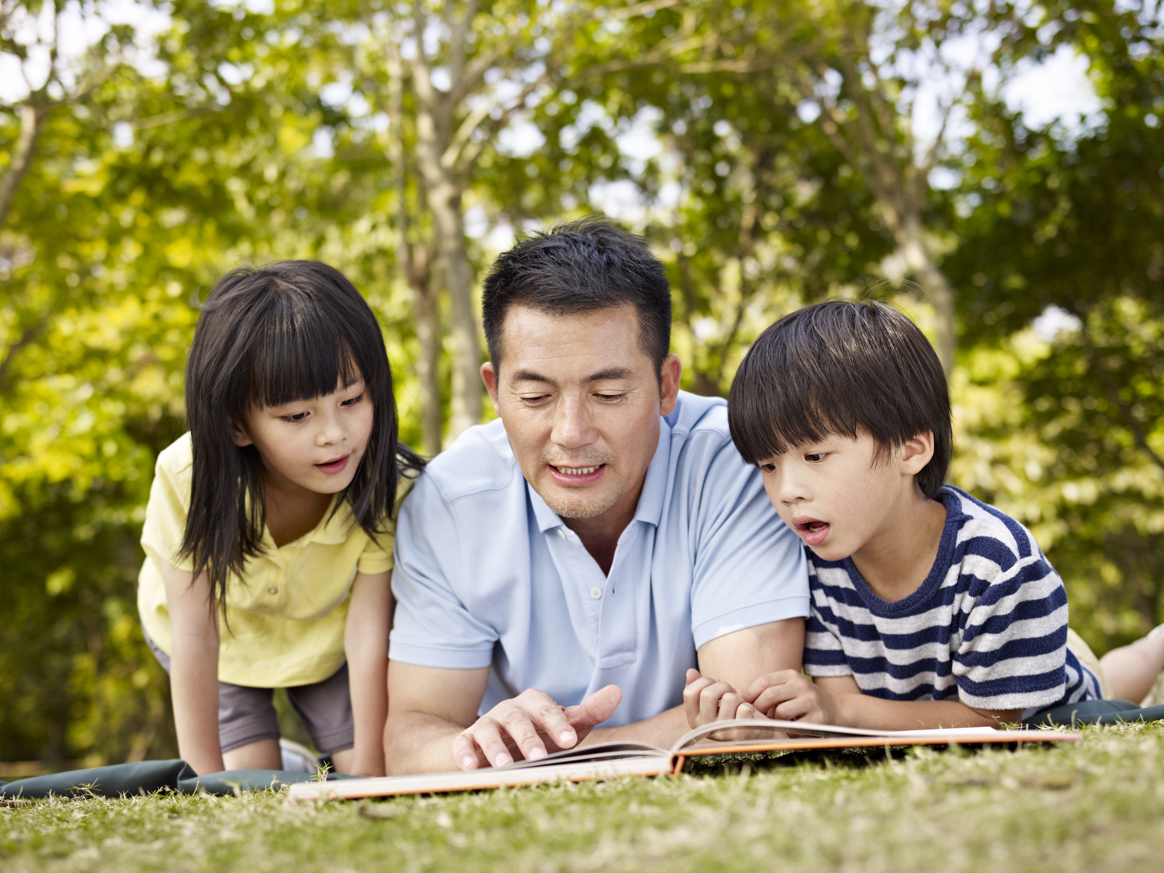 Father and children reading book together