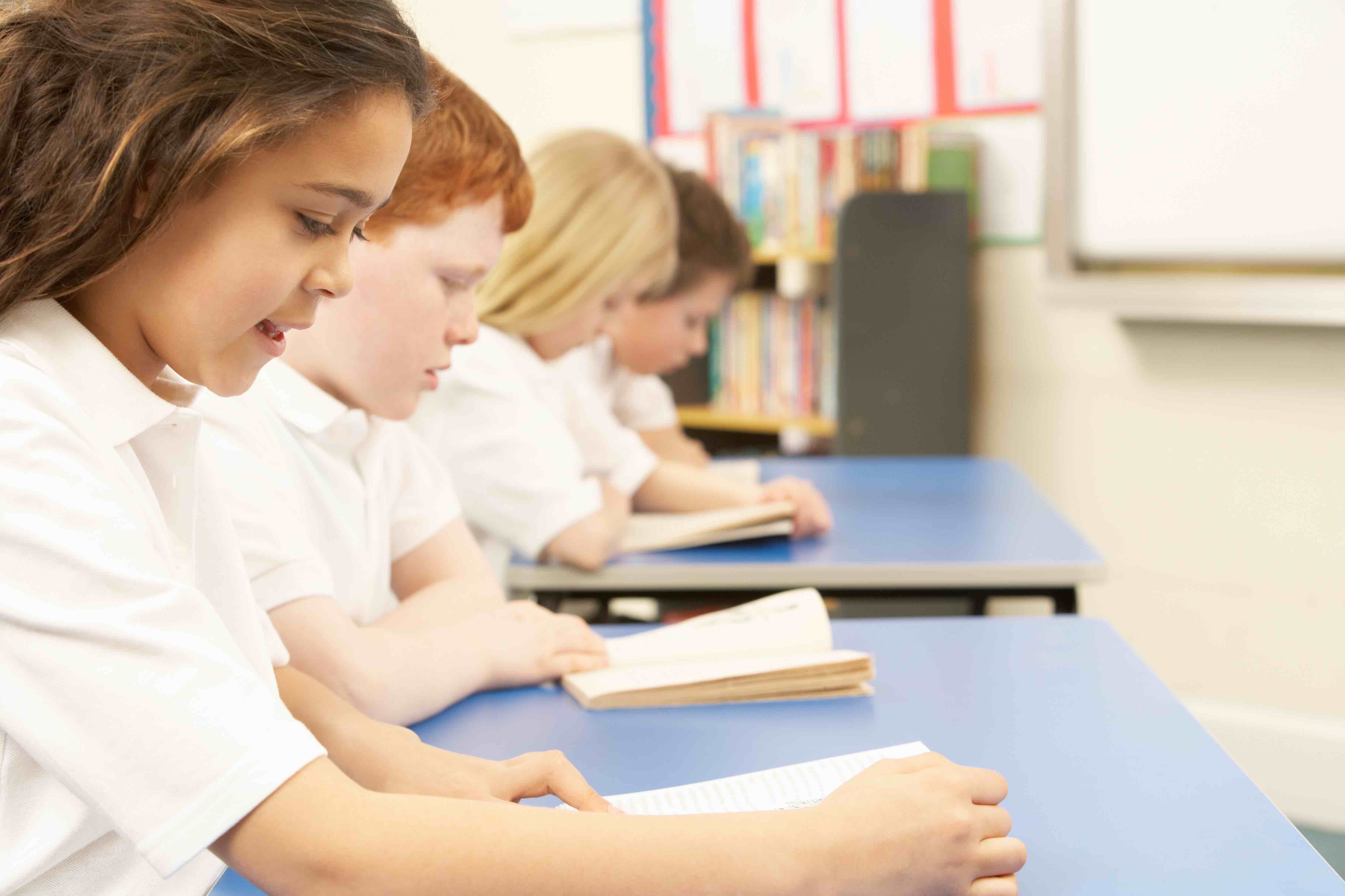 Group Of Children Reading Books In Classroom