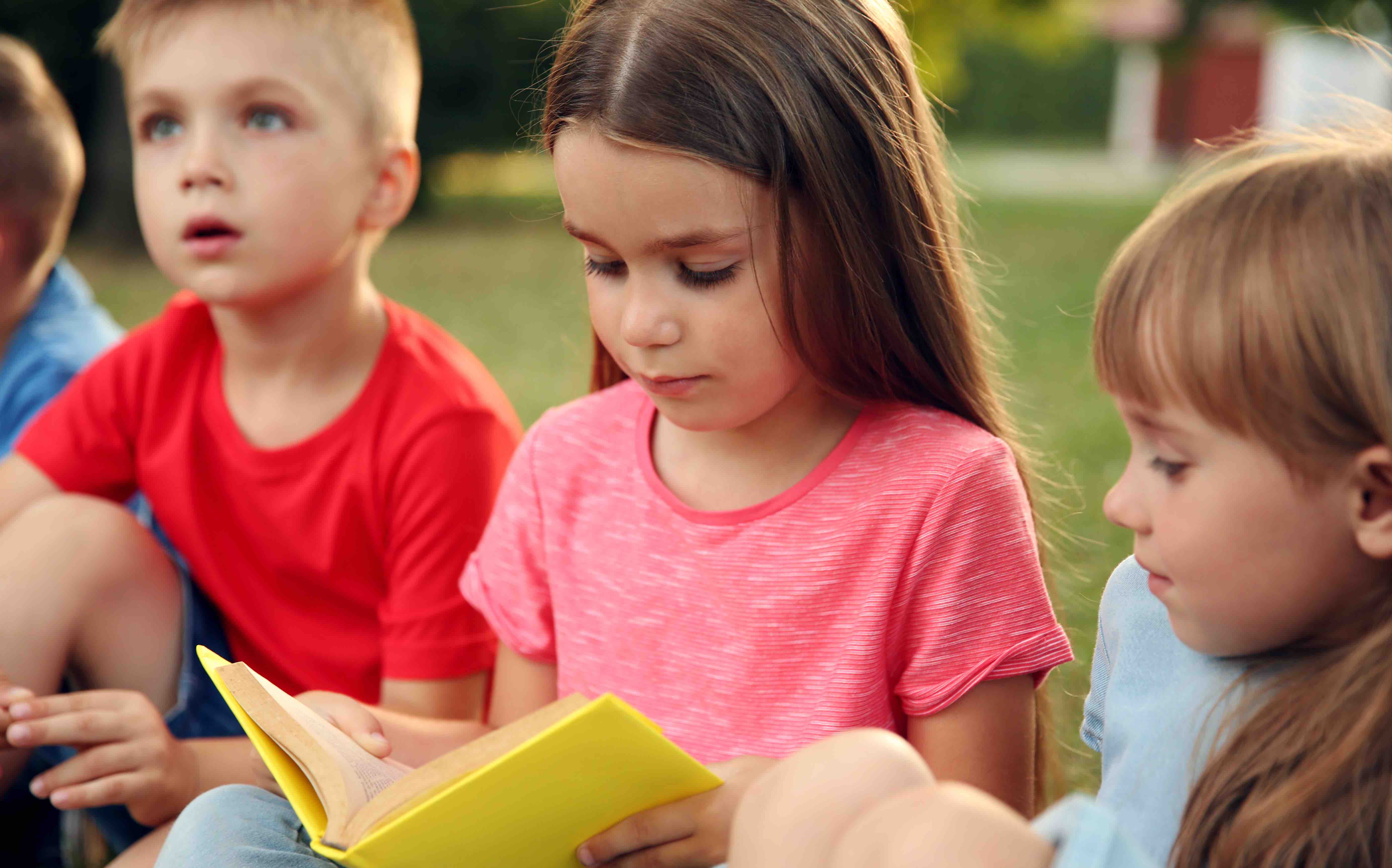 Group of happy kids reading books in park