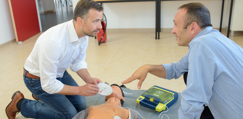 Men training to use defibrillator