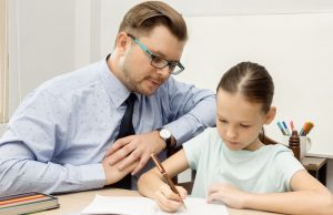 Young teacher and schoolgirl writing in classroom