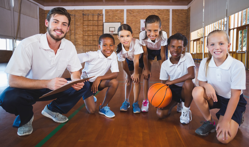 Portrait of sports teacher and school kids in basketball court