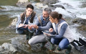 Biologist with students in science testing river water