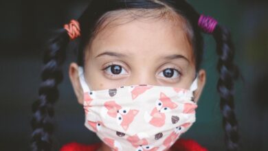 Young girl with two long plaits wearing fabric facemask covered in fox print