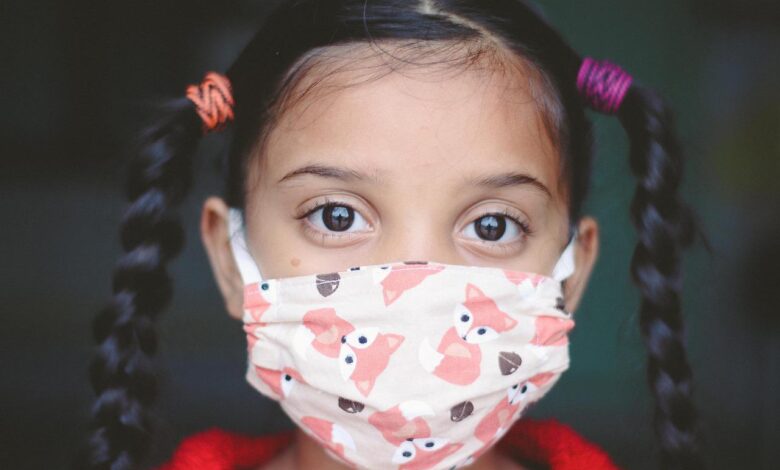 Young girl with two long plaits wearing fabric facemask covered in fox print