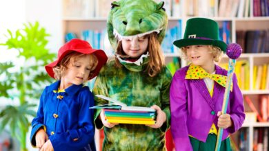 Three young children wearing costumes looking at books