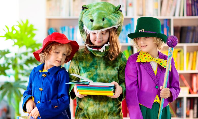 Three young children wearing costumes looking at books