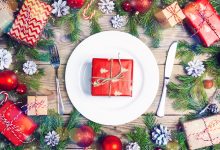 Festive table setting with wrapped gift on dinner plate, with knife and fork on either side