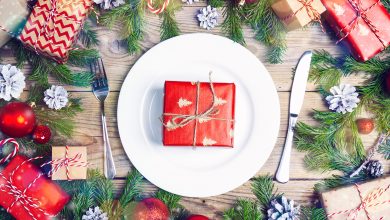 Festive table setting with wrapped gift on dinner plate, with knife and fork on either side